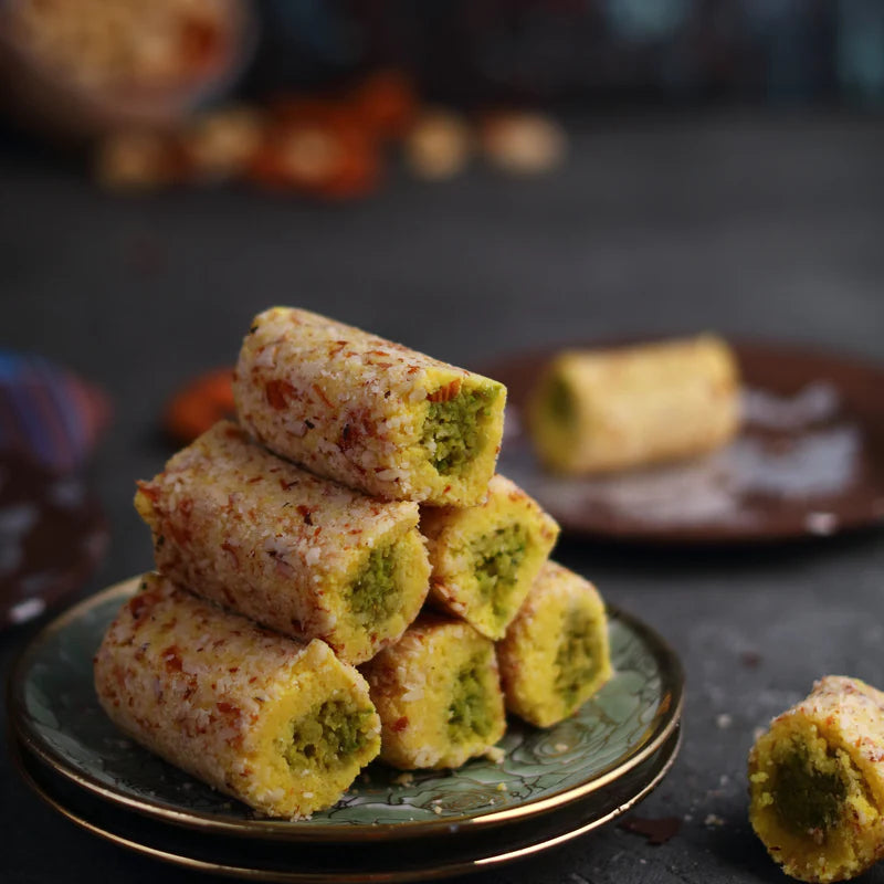 Almond House Badam Kesar Roll stacked on a plate with a visible pistachio filling.
