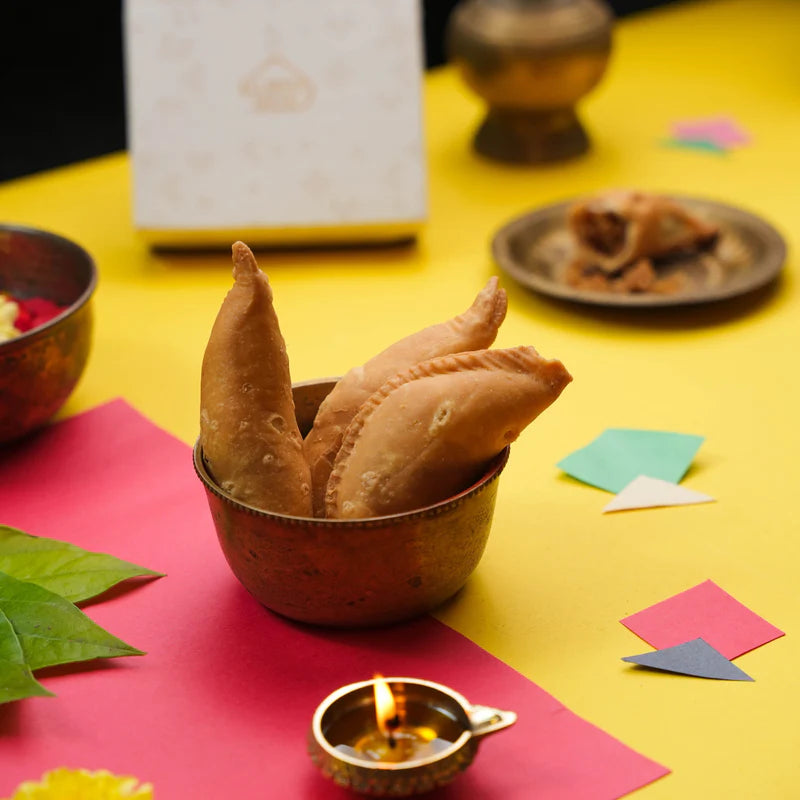 Festive presentation of Almond House Bellam Kajjikayalu in a brass bowl, perfect for celebrations.