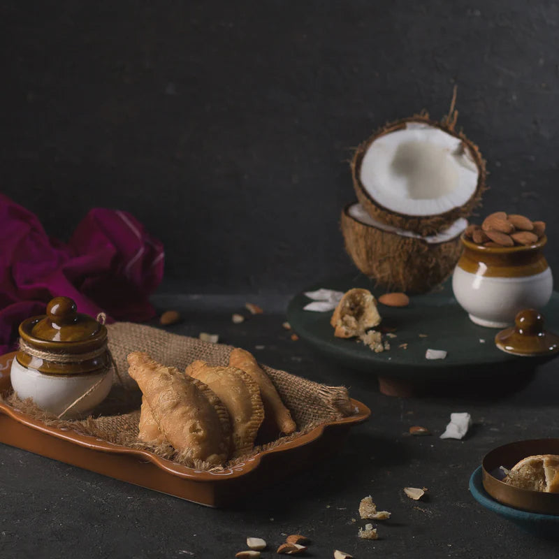 Almond House Bellam Kajjikayalu filled with jaggery and coconut, displayed with traditional ingredients.