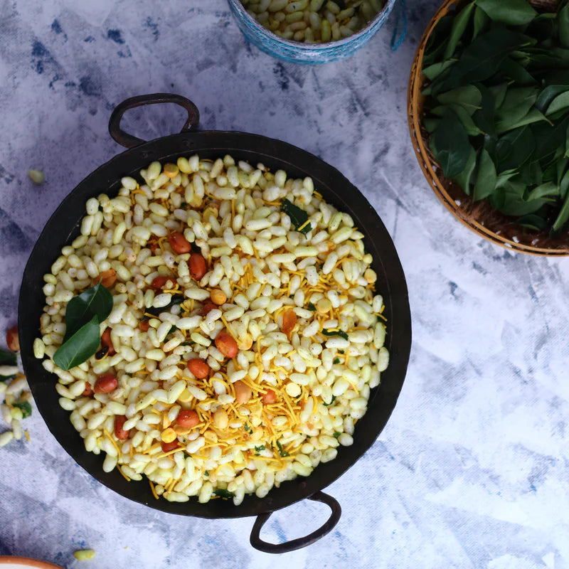Bowl of Almond House Murmura Chudwa – puffed rice snack with sev, peanuts, and curry leaves on a rustic table.